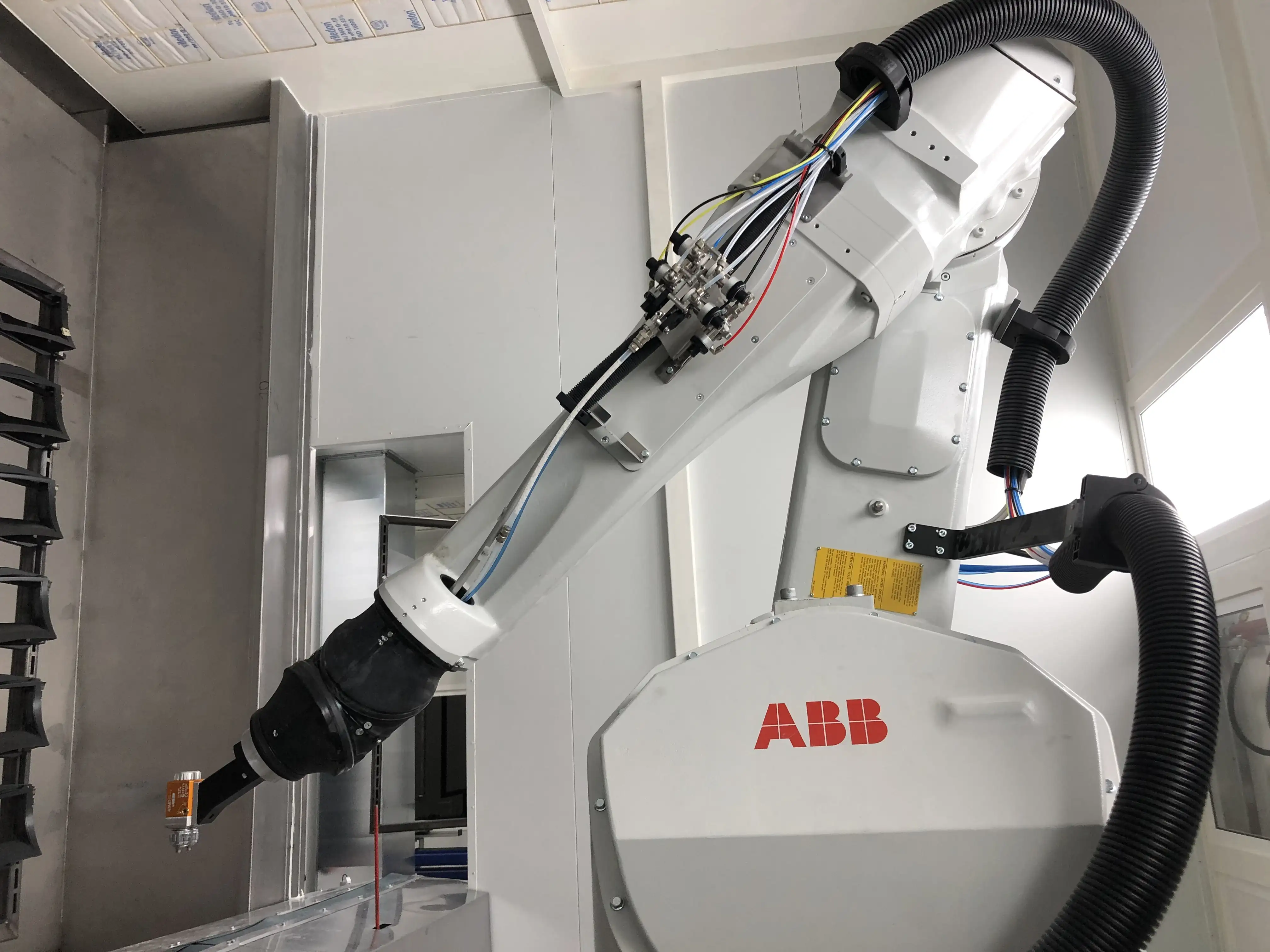 Imagen de una cabina de pintura automática con sistema húmedo de cortina de agua y robots automatizados aplicando pintura en línea de producción automotriz.